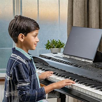 a young boy playing a musical keyboard taking high quality piano classes on Zoom