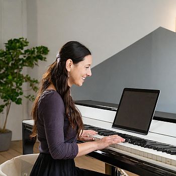 a young woman taking an online piano lesson for are piano lessons worth it.