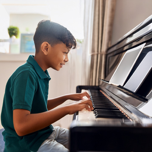 Boy playing piano while Taking an online live lesson with jackie clark